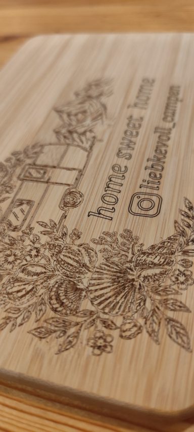 Holzbrett mit floralem Muster und Instagram-Handle eingraviert.